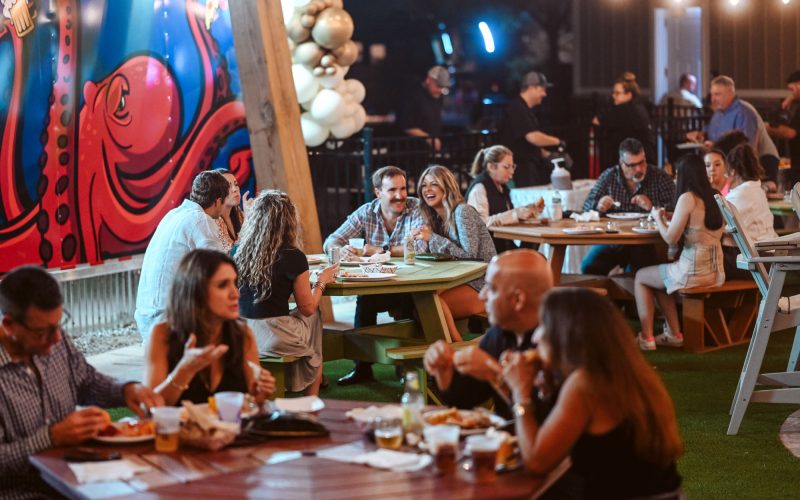 Guests share food and drinks at evening gathering with octopus mural at Splash RV Resort in Milton, Florida