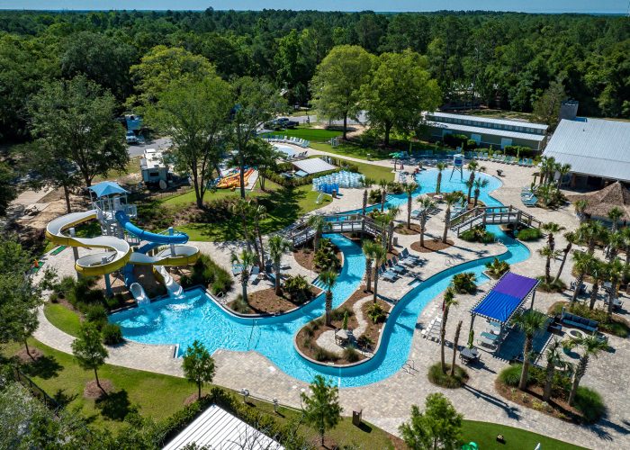 Aerial view of Splash RV Resort water park with lazy river twisting yellow and blue waterslides and shaded cabanas